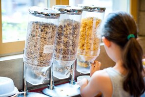 Une personne se tient devant un distributeur de nourriture muni de trois récipients étiquetés avec différents types d’aliments.