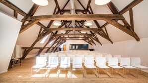 An interior with wooden beams, white chairs, and a visible reception area in the background. - Liège Youth Hostel (Liege)