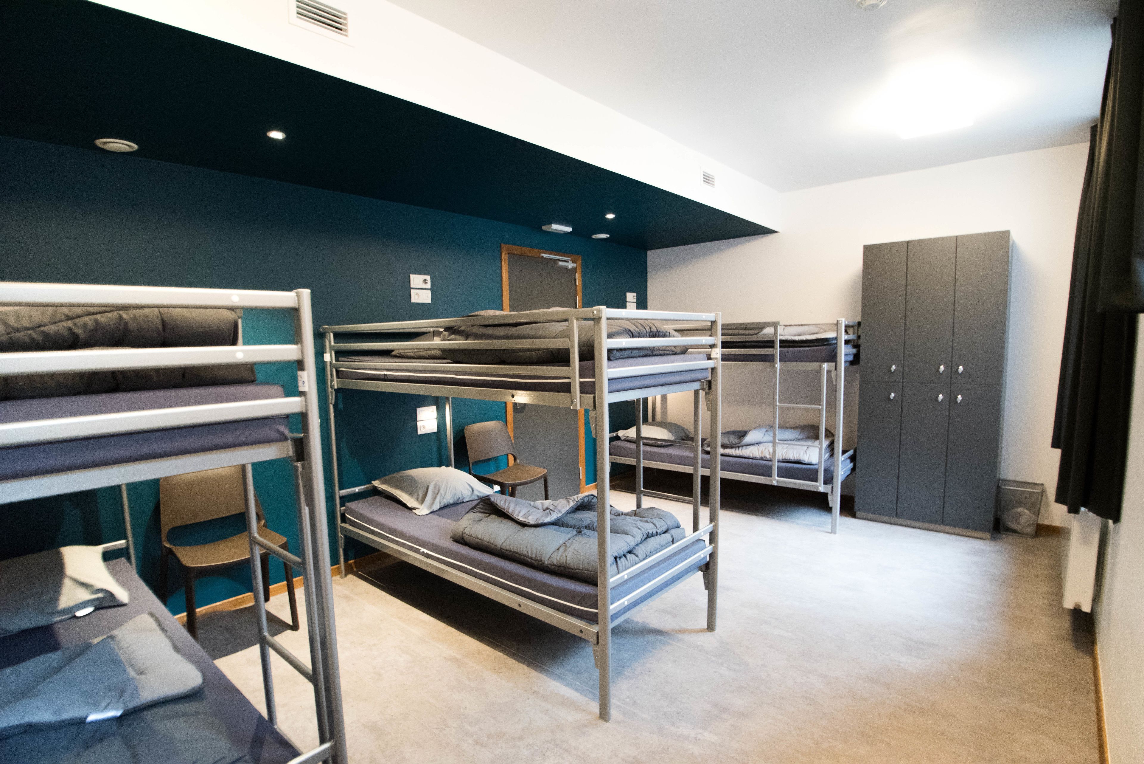 Un dormitorio con literas, un escritorio, una silla y un armario.