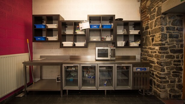 A kitchen with stainless steel appliances, storage cabinets, and a microwave. - Liège Youth Hostel (Liege)
