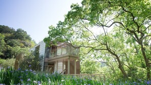 A modern two-story house surrounded by lush greenery and purple flowers. - ChooArt Villa (Sanyi)