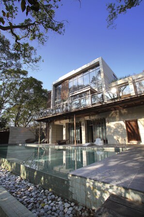 Una casa moderna de dos pisos con piscina, ventanas grandes y balcón.