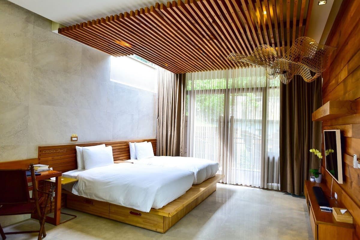 A modern bedroom with a large bed, wooden headboard, and a slatted ceiling design.