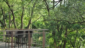 A glass-enclosed outdoor deck with seating, surrounded by dense forest. - ChooArt Villa (Sanyi)