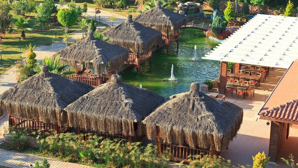 A resort with thatched-roof huts, a pool, and a dining area. - Club Mermaid Village  (Alanya)