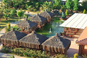 A resort with thatched-roof huts, a pool, and a dining area. - Club Mermaid Village  (Alanya)