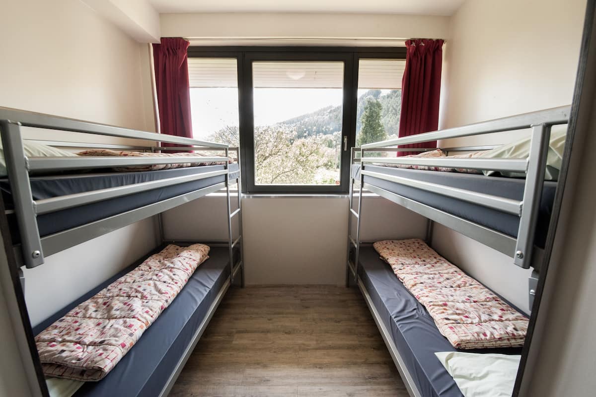 Una habitación pequeña y estrecha con dos literas y una ventana.