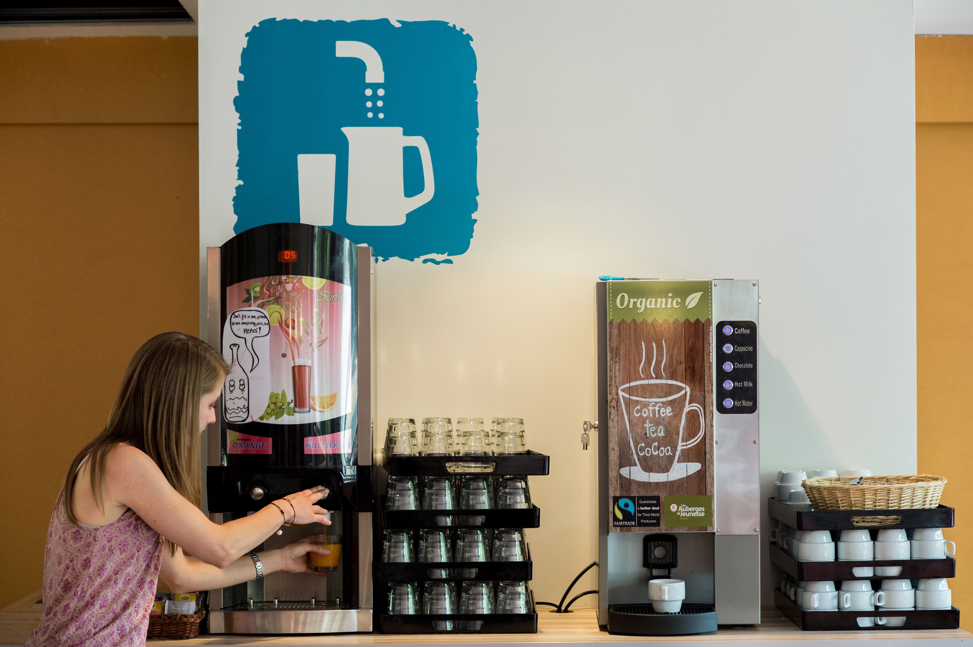 A coffee machine with a variety of drink options, a coffee cup display, and a basket of cups.