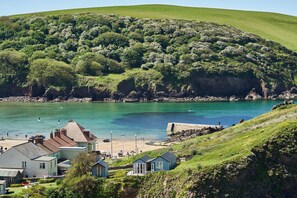 A coastal village with houses, a beach, and a rocky shoreline. - Hope & Anchor (Kingsbridge)