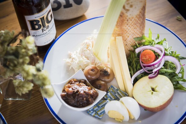 A plate with various food items including bread, cheese, salad, and a bottle of beer.