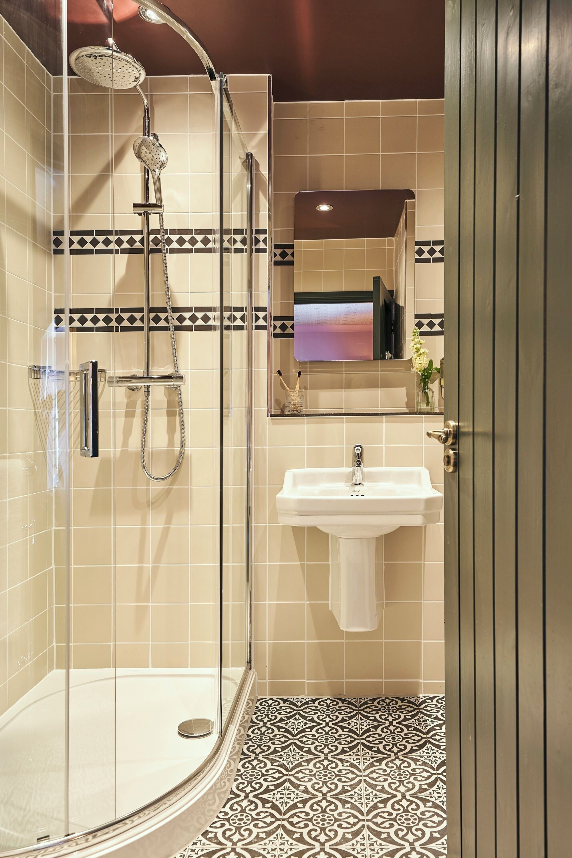 A modern bathroom with a glass-enclosed shower, a white sink, and a decorative tile backsplash.