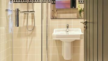 A modern bathroom with a glass-enclosed shower, a white sink, and a decorative tile backsplash.