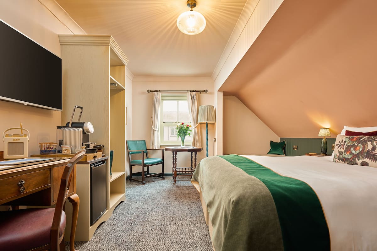 Ein Hotelzimmer mit Bett, Schreibtisch, Stuhl und Fernseher.