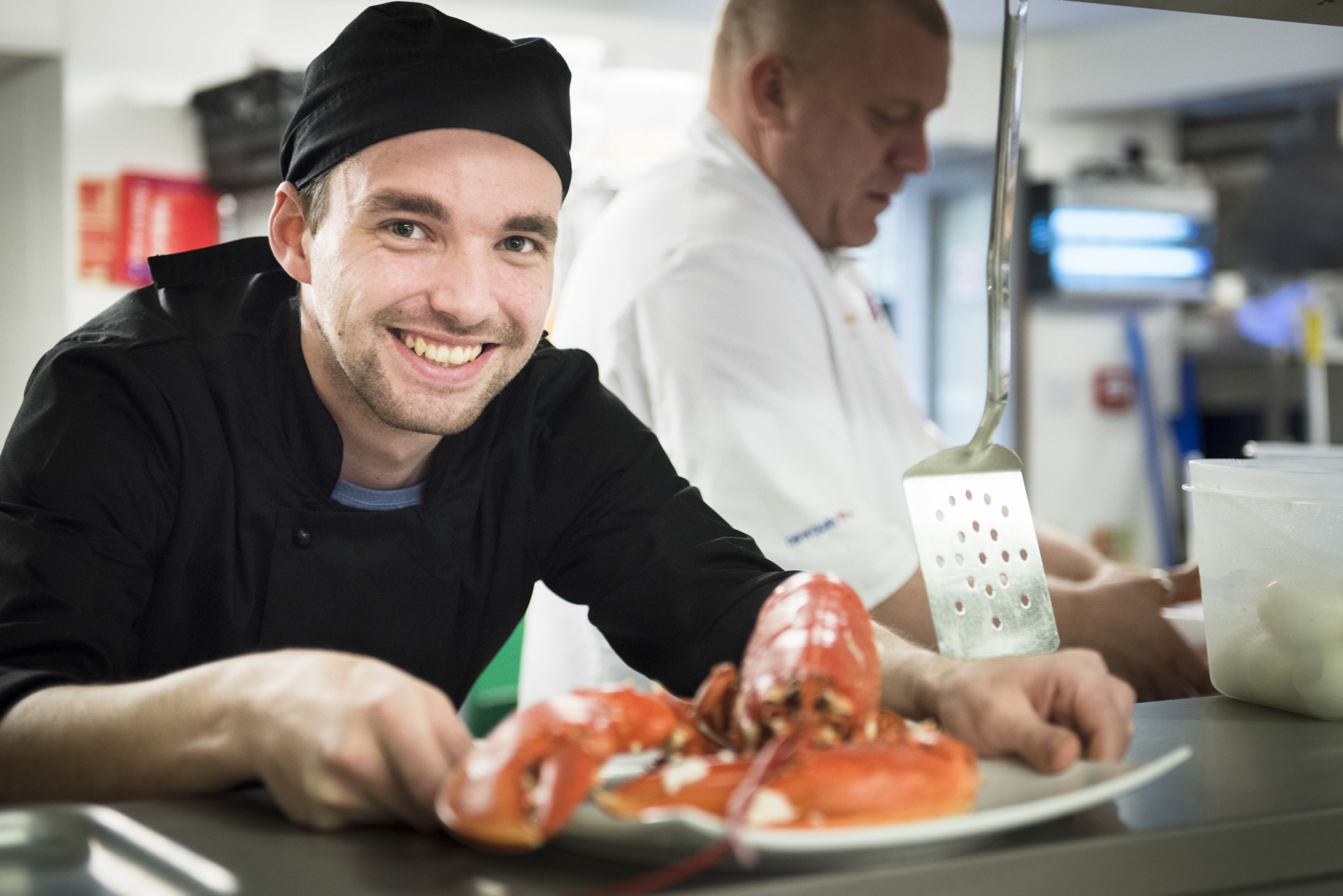 Een kok bereidt kreeft in een keuken.