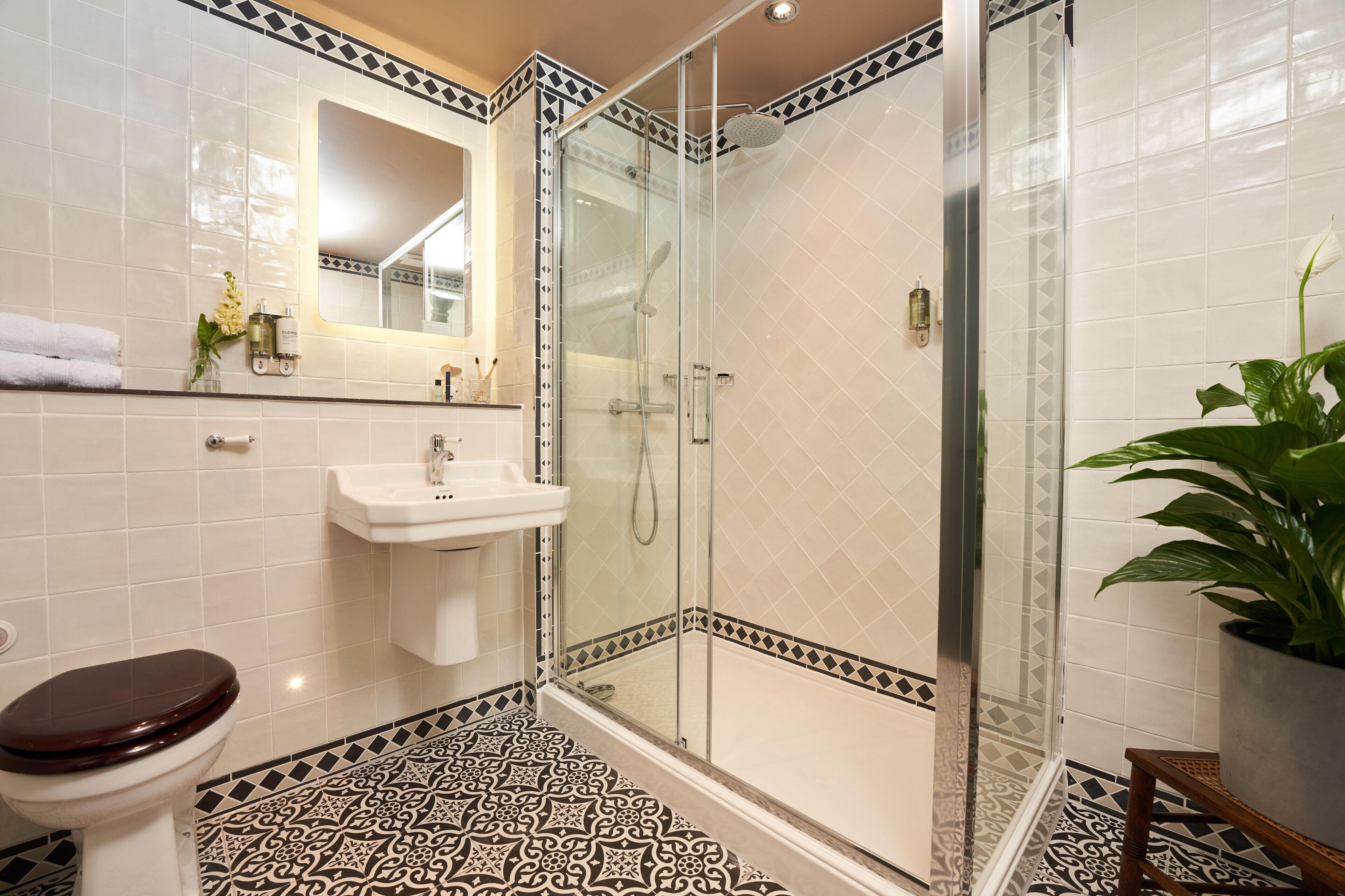 Une salle de bain comprenant des toilettes, un lavabo et une douche fermée par des parois en verre.