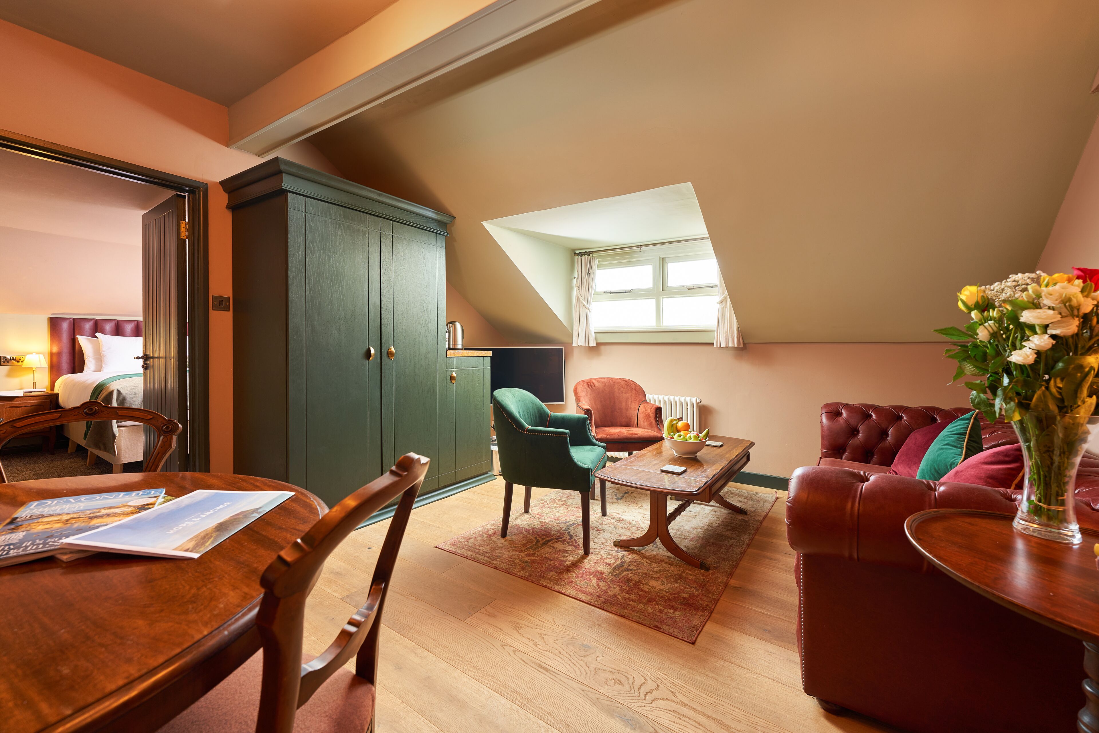 A cozy living room with a dining area, a green cabinet, and a red sofa.