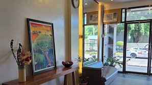 A reception area with a wooden bench, a framed painting, and potted plants. - First Pacific Inn (Davao)