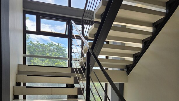A modern staircase with a glass railing, leading to an upper floor. - First Pacific Inn (Davao)