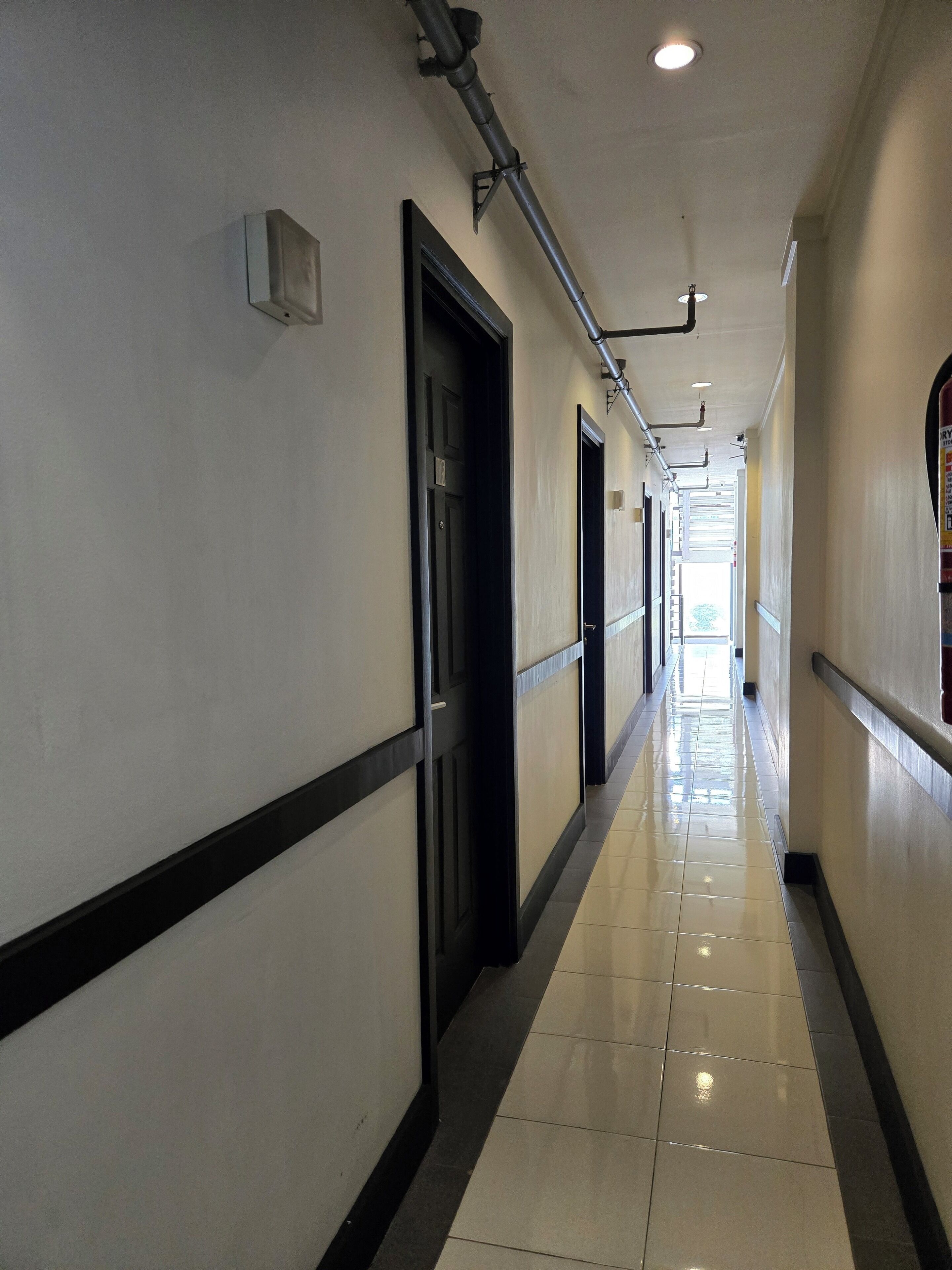 A long, narrow hallway with a tiled floor and black door frames.