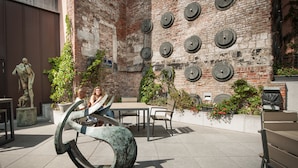 An outdoor seating area with a brick wall, circular wall decorations, and a sculpture.