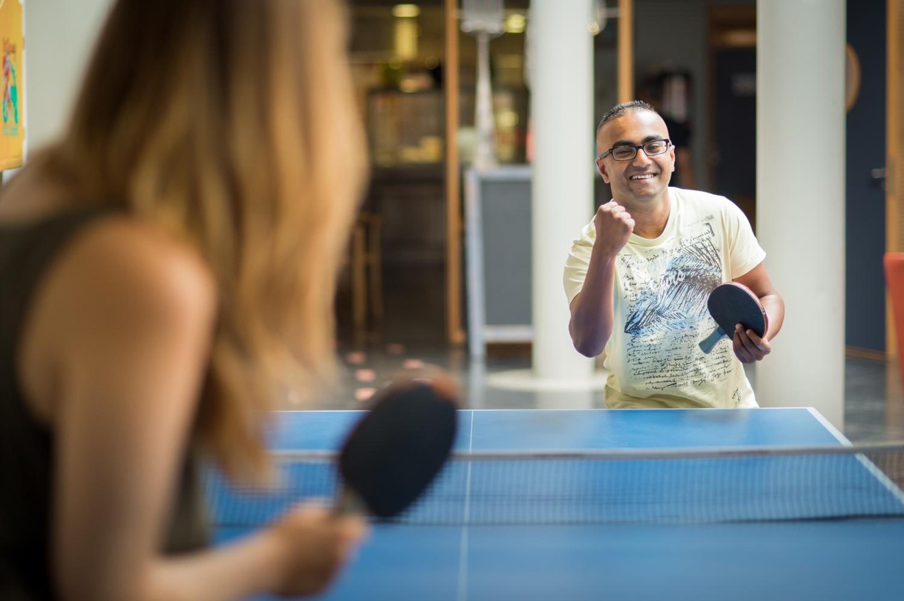 A person playing table tennis indoors.