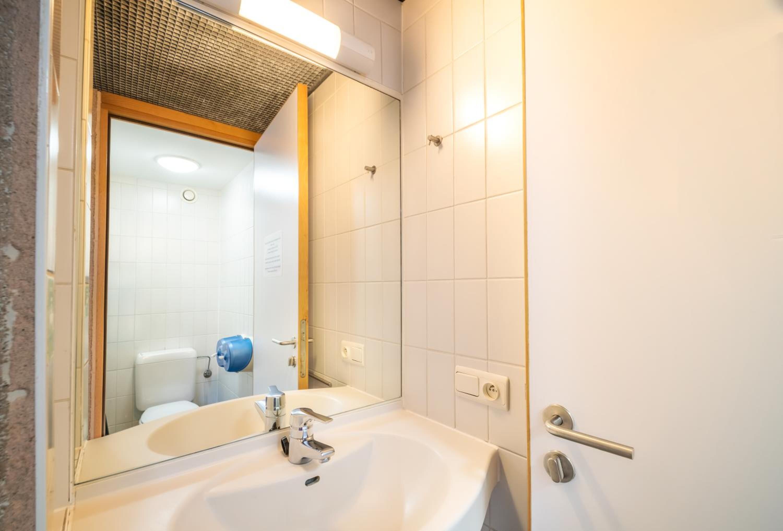 A bathroom with a white sink, a mirror, and a shower door.