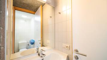 A bathroom with a white sink, a mirror, and a shower door.