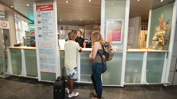 A reception area with a glass partition, a reception desk, and a sign with information.