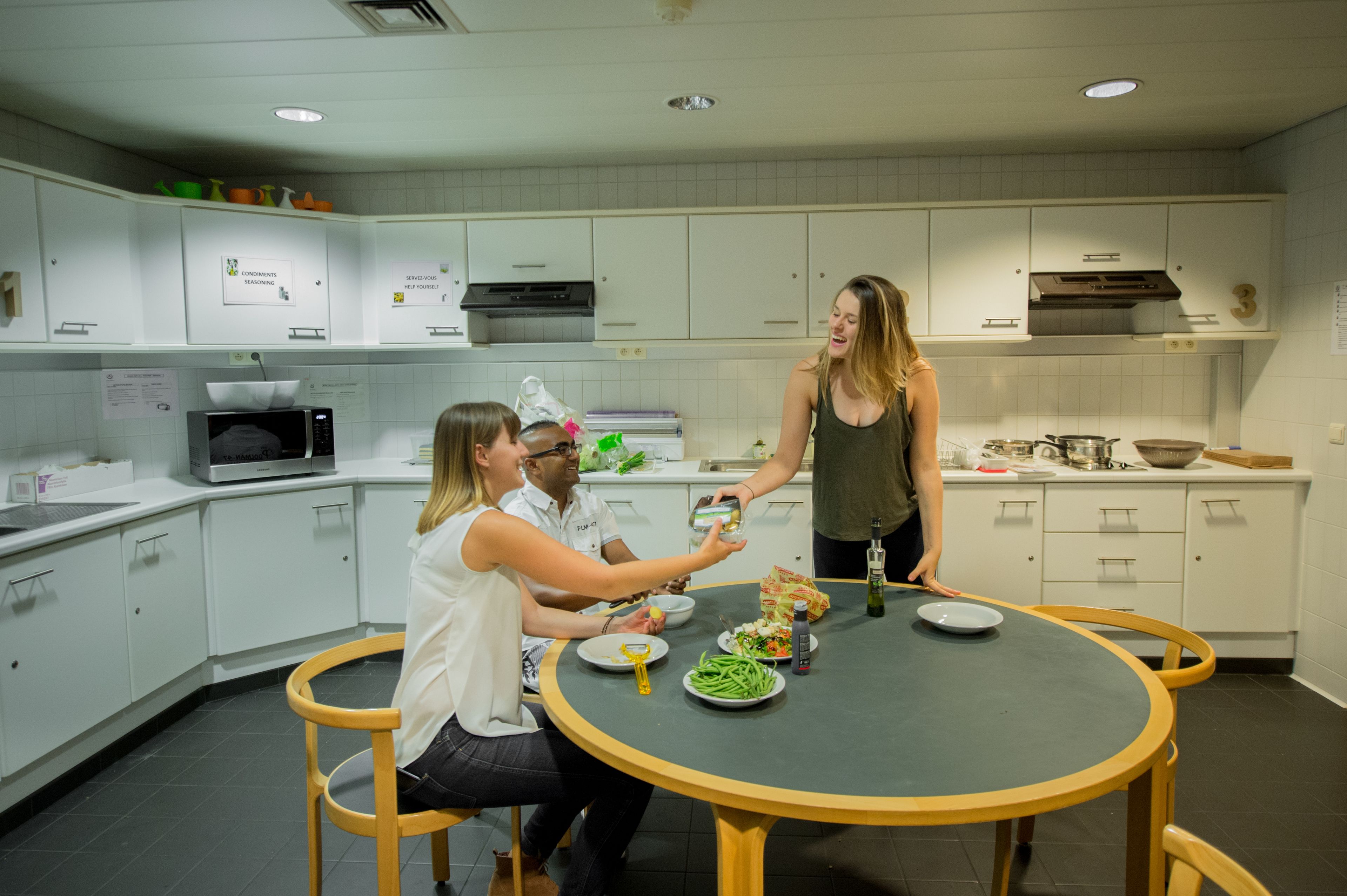 Una cocina moderna con armarios blancos, microondas y una mesa de comedor con sillas.