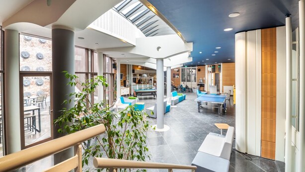 A spacious indoor area with a pool table, seating areas, and a skylight.