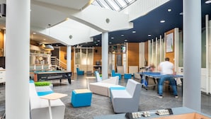 A modern indoor space with a billiards table, seating areas, and a pool table.