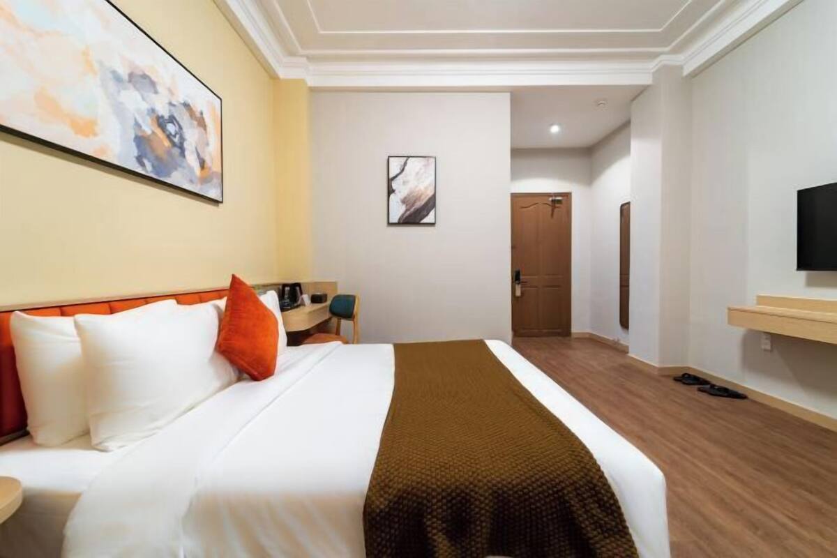 Ein Hotelzimmer mit einem Bett, einem Schreibtisch, einem Stuhl, einem Fernseher und einer Tür.