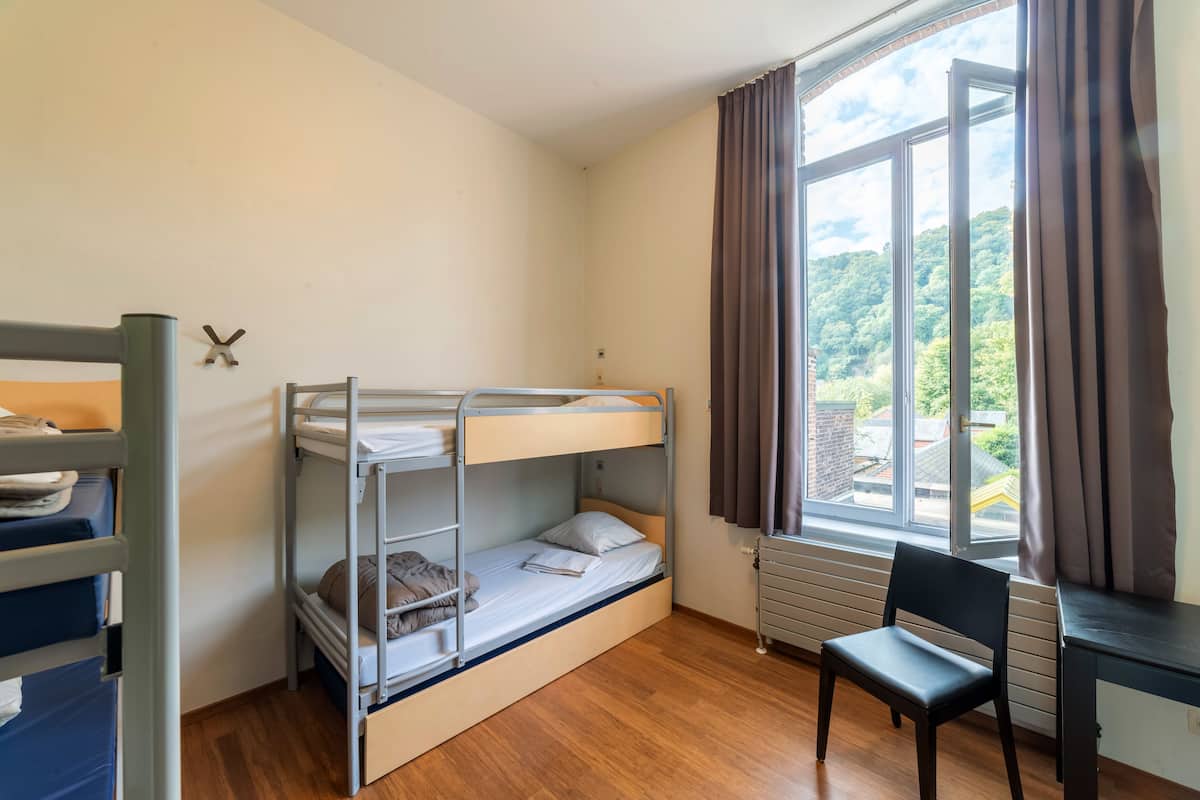 Une chambre avec un lit superposé, une fenêtre, un bureau et une chaise.