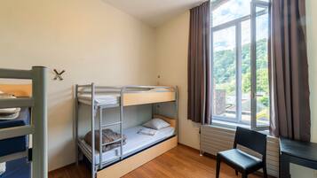 Een slaapkamer met stapelbed, raam, bureau en stoel.