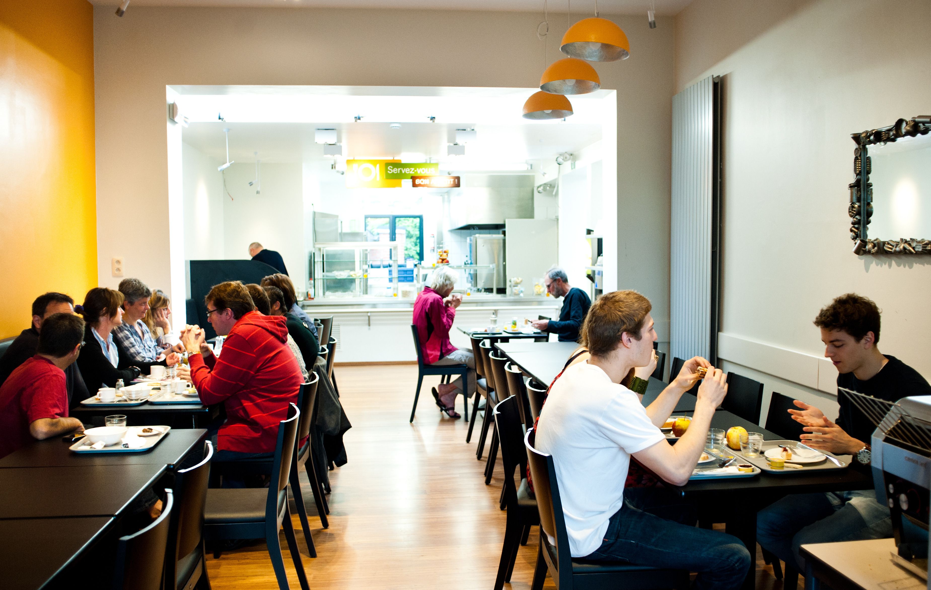 A dining area with tables and chairs, a counter with a menu, and a mirror on the wall.