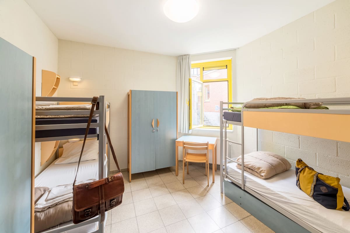 Une chambre de dortoir équipée de lits superposés, d’un bureau, d’une chaise et d’une armoire.