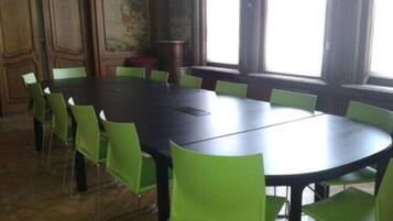 Uma sala de conferências com uma mesa grande e cadeiras verdes.