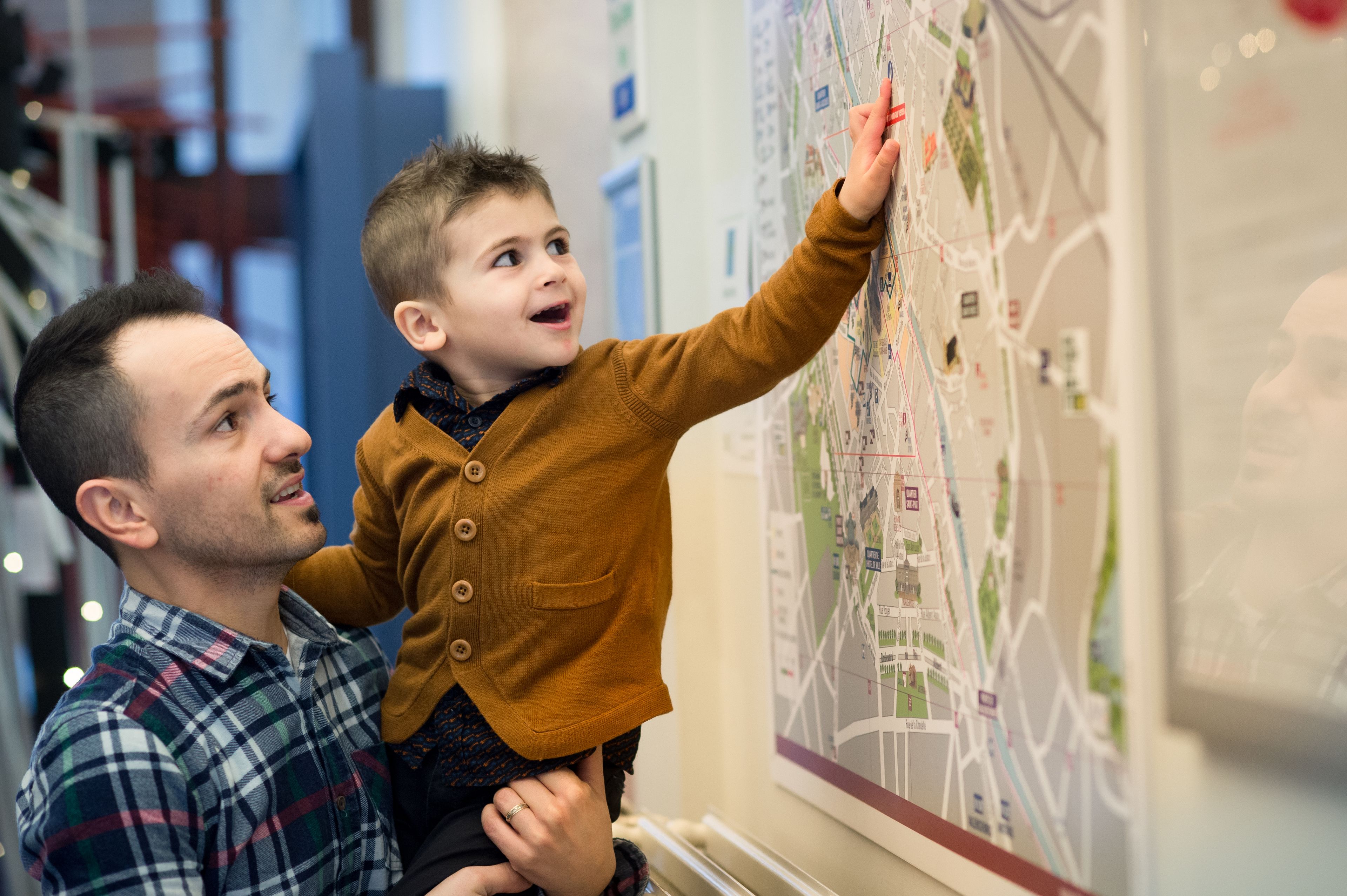 Un hombre y un niño observando un mapa grande en la pared.
