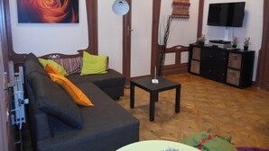 Una sala de estar con un sofá, una mesita, un televisor y un mueble aparador.