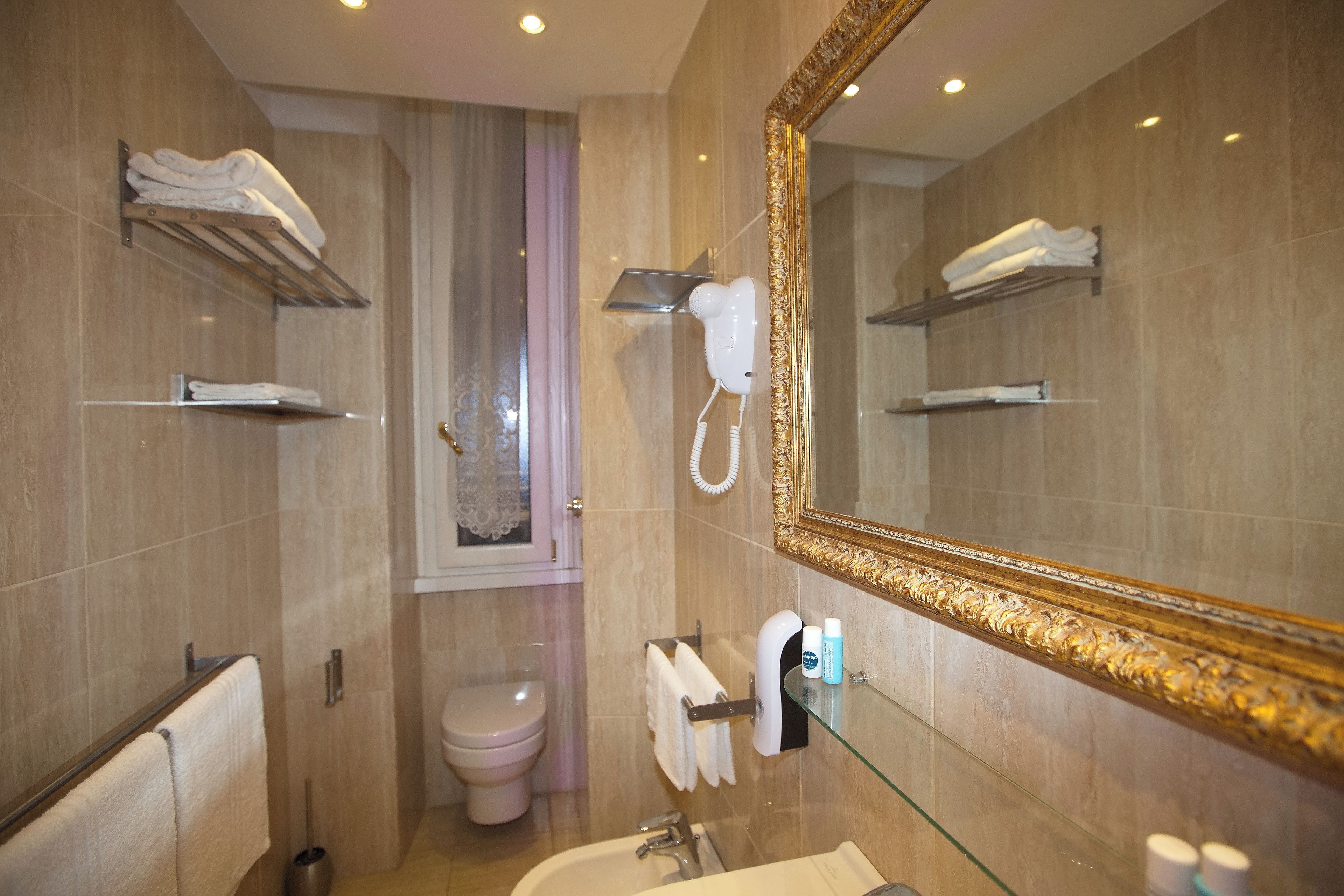 Une salle de bain avec un grand miroir, des porte-serviettes, des toilettes et un sèche-cheveux.