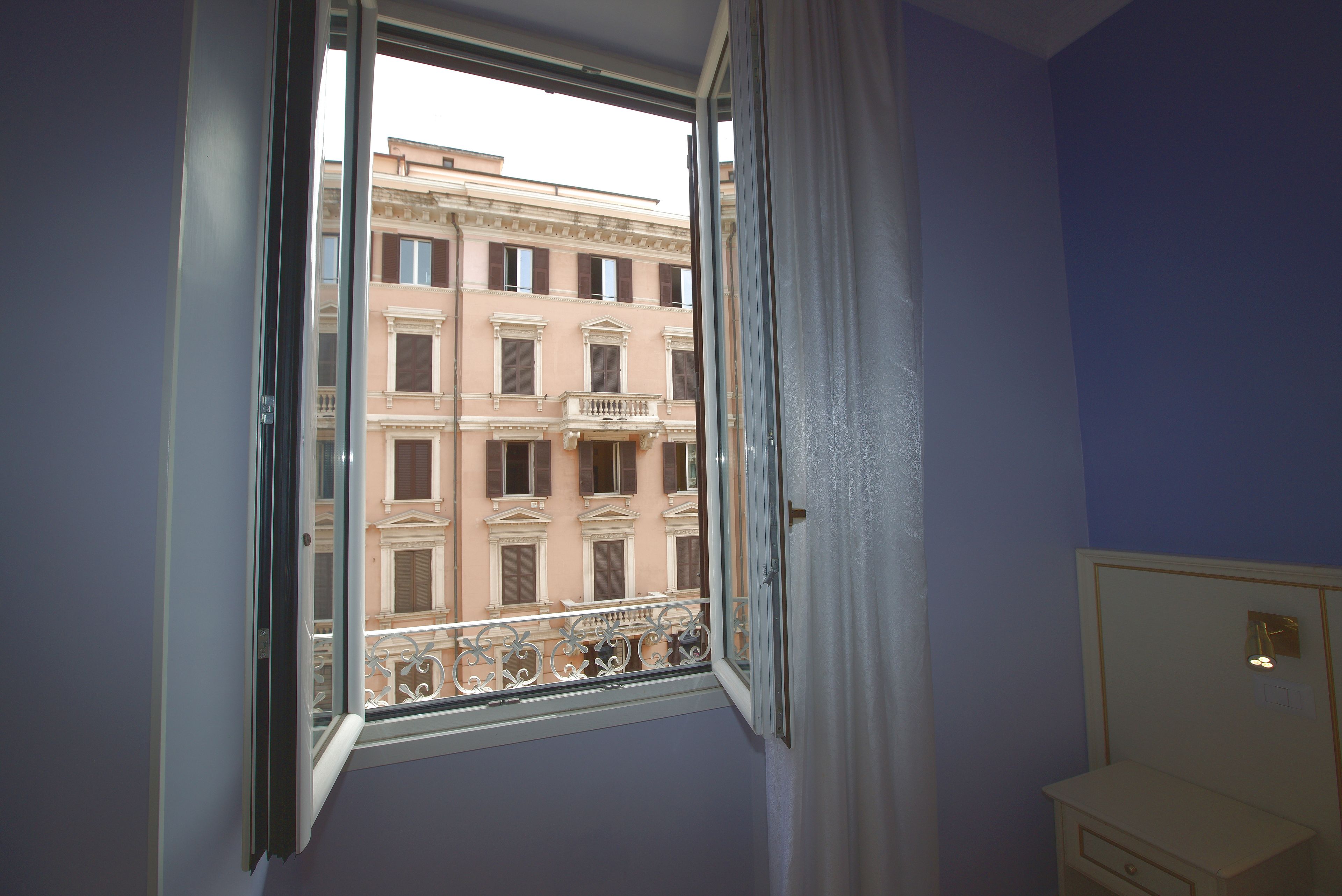 A room with a window overlooking a building with multiple windows and balconies.