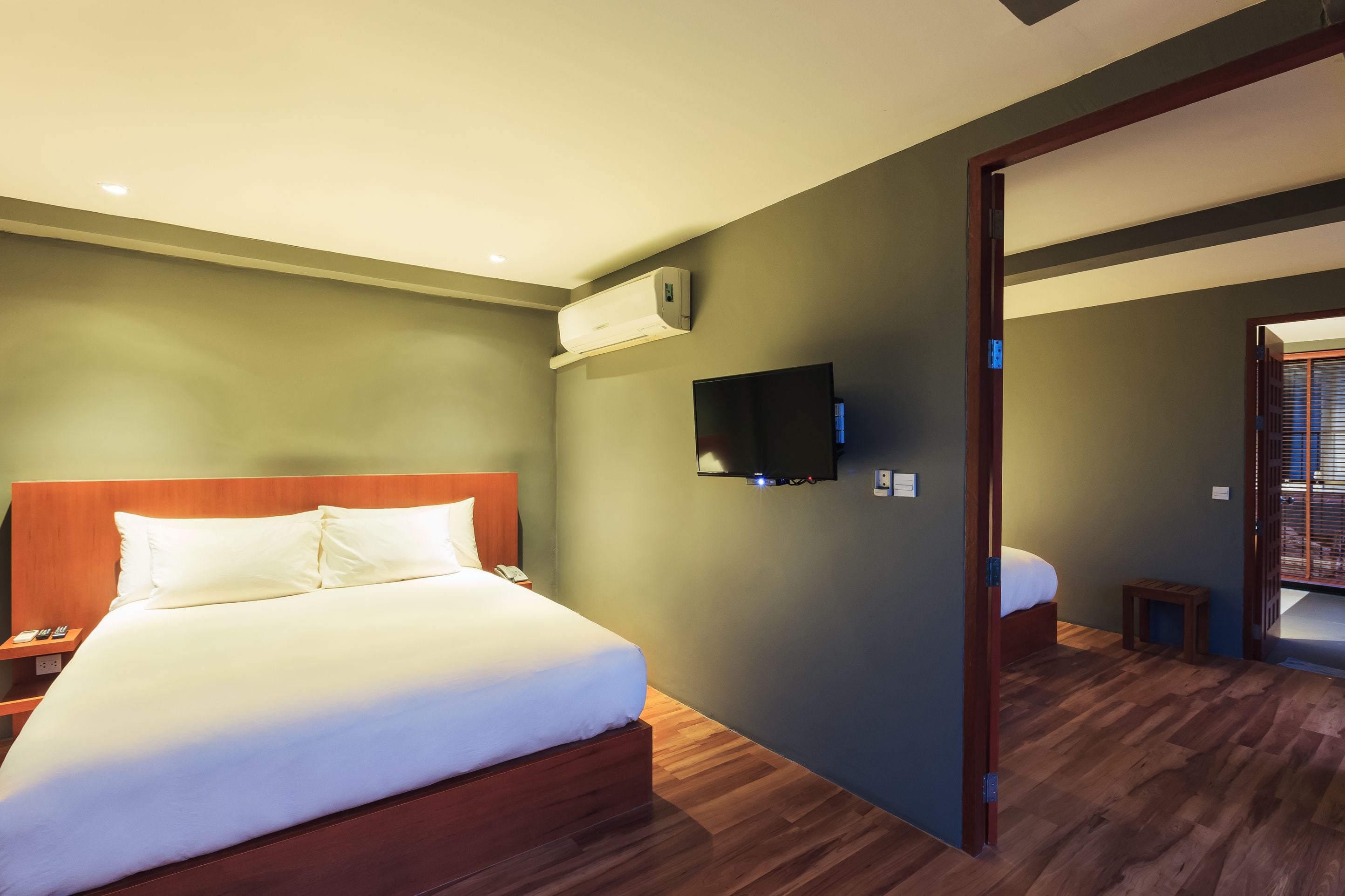 Ein Hotelzimmer mit einem hölzernen Bett, einem flachbildfernseher an der Wand und einem kleinen Holztisch.