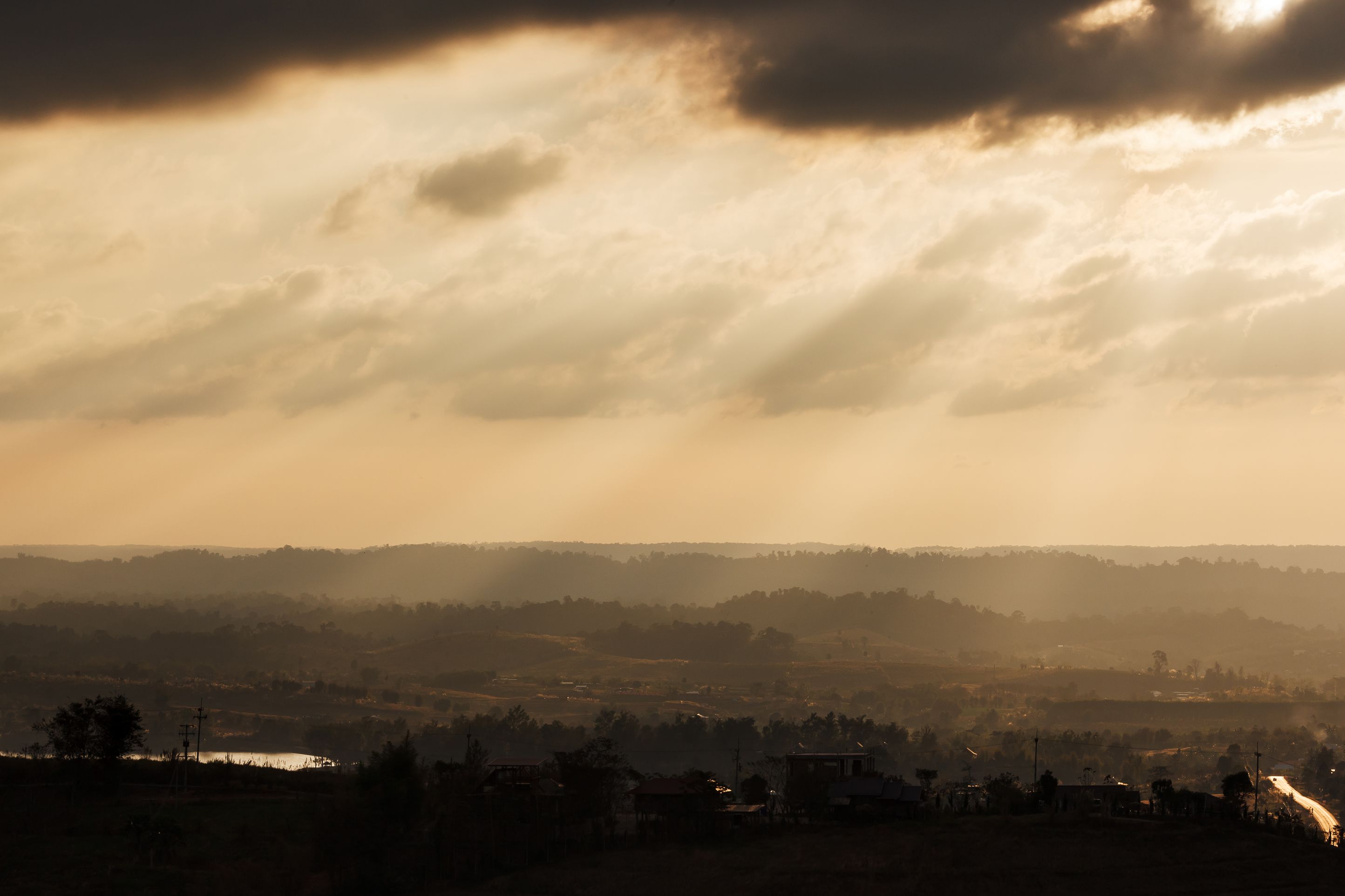 Ein weiter Panoramablick über ein Tal mit einer in der Ferne liegenden Stadt und einem Gewässer.
