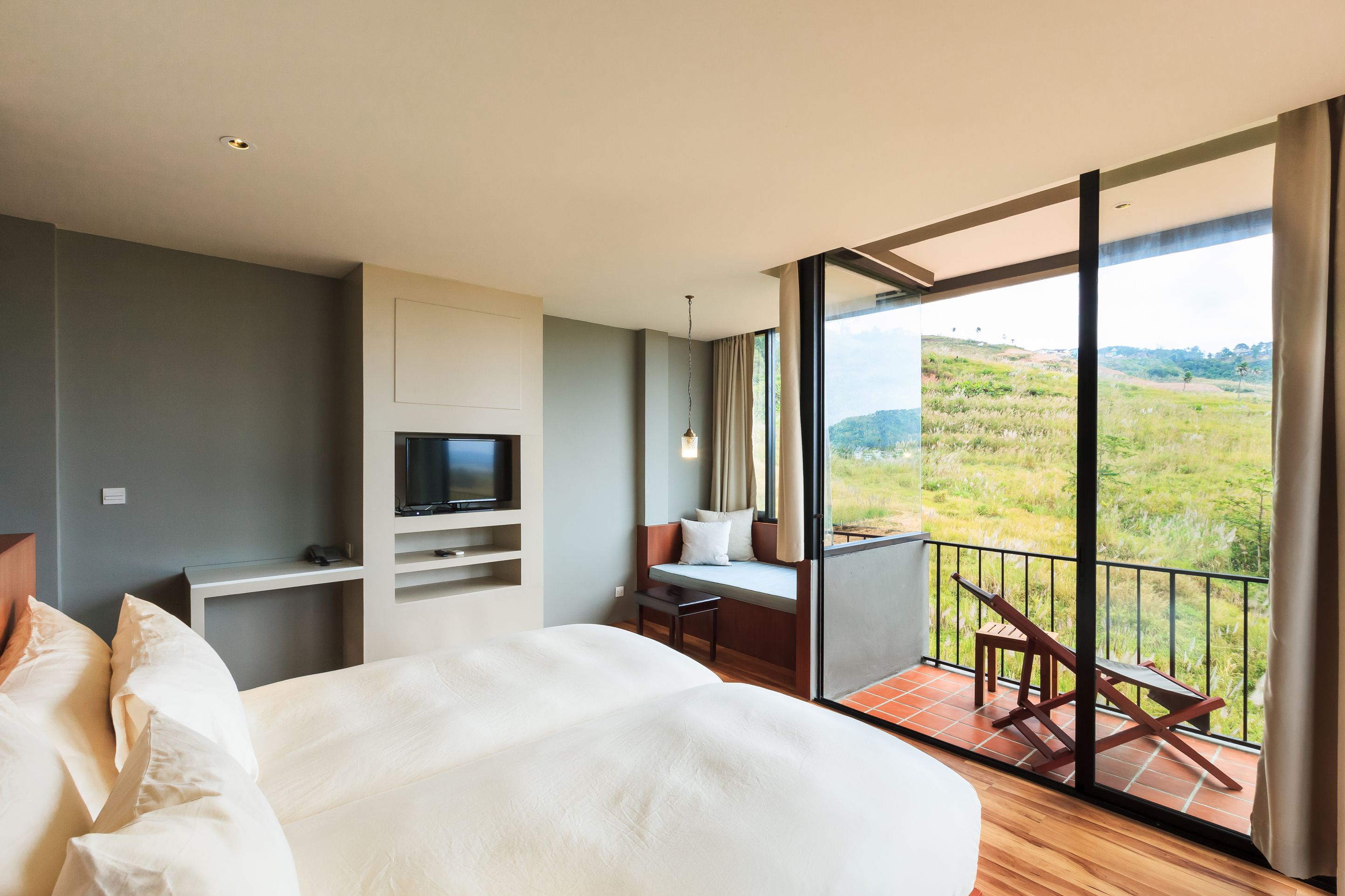 Une chambre d’hôtel moderne dotée d’un grand lit, d’une télévision, d’un coin salon avec vue et d’un balcon.