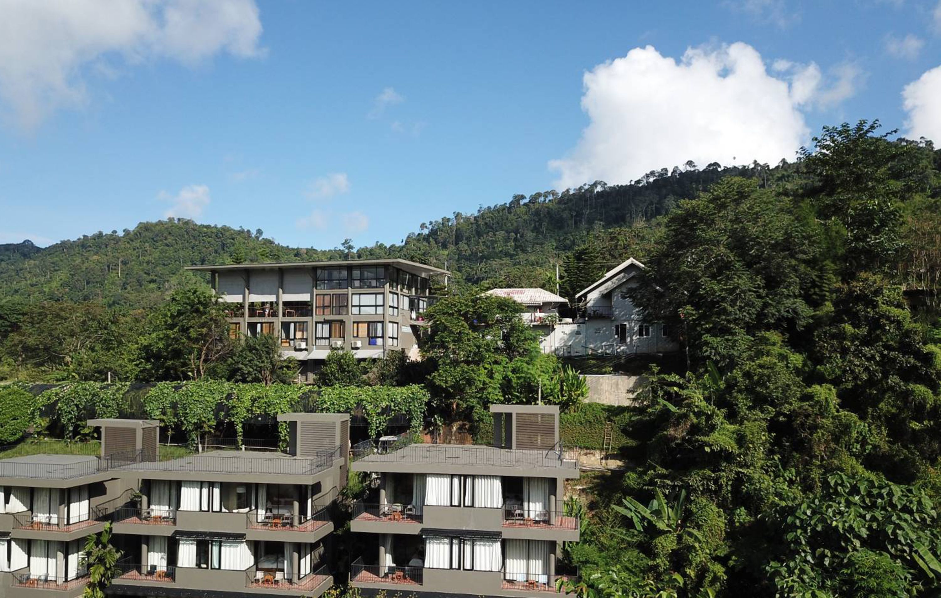 Un hotel de varios pisos con balcones, ubicado en una zona montañosa y exuberante.