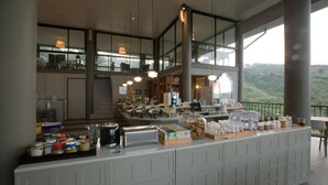 A breakfast buffet with various food items, a coffee station, and a view of the surrounding landscape. - Sirinati Khao Kho National Park (Khao Kho)