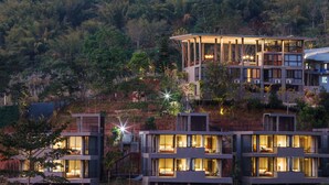 A modern multi-story hotel with multiple balconies and large windows, set against a forested hillside. - Sirinati Khao Kho National Park (Khao Kho)