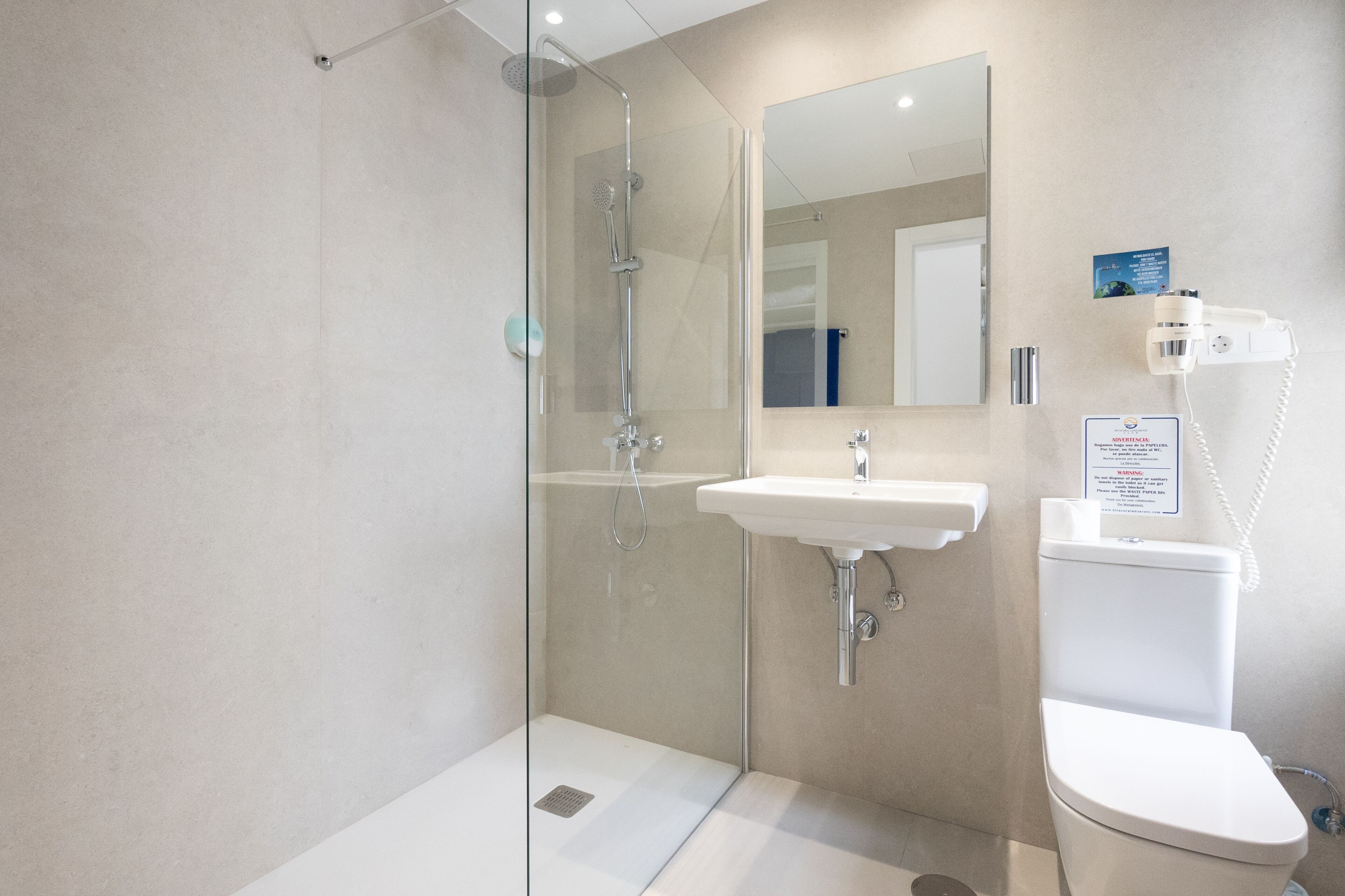 Une salle de bain moderne avec une douche à parois de verre, un lavabo et des toilettes.