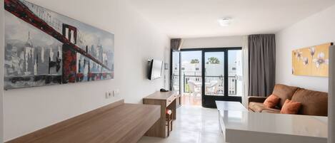 Una sala moderna con un sofá, una mesa de comedor y una zona de cocina.