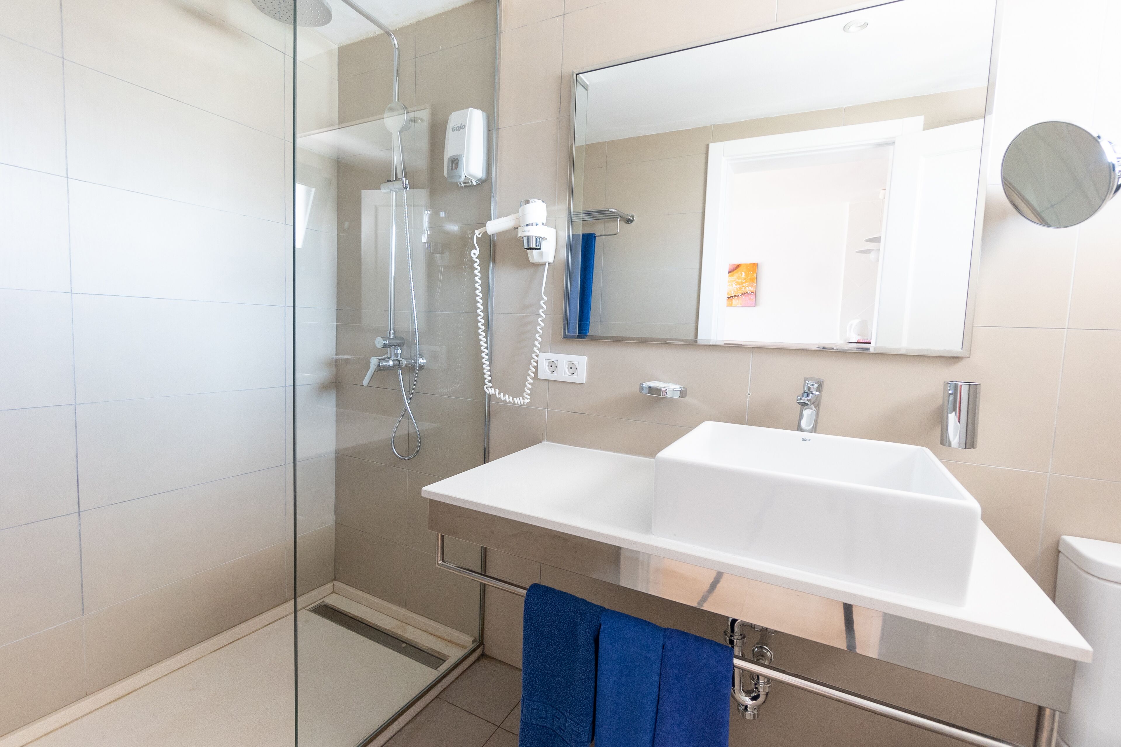 Un baño moderno con cabina de ducha de vidrio, un lavabo blanco y un espejo grande.
